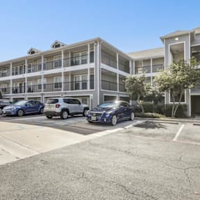 A parking lot with cars and a building in the background.