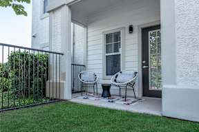 two chairs on a patio in front of a house
