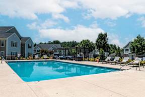 A swimming pool in a residential area with houses in the background.