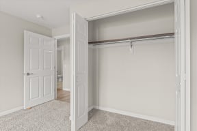 an empty bedroom with an open closet and a door to the bathroom