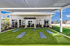 A yoga studio with a white roof and a green lawn in front.