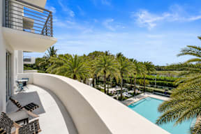 A modern building with a pool and palm trees in the background.