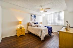 A bedroom with a bed, nightstand, and a ceiling fan.