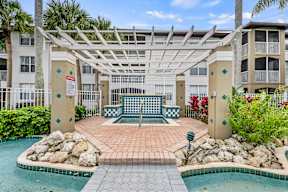 A pool area with a pergola and a bench.