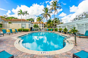 A swimming pool surrounded by palm trees and lounge chairs.