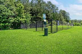 A green sign is on a fence in a grassy area.
