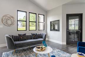 A grey couch with a blue chair and a table with a bowl on it.