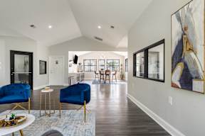 A modern living room with blue chairs and a painting on the wall.
