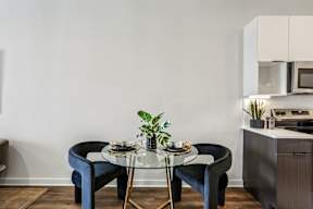 A modern dining area with a glass table and blue chairs.