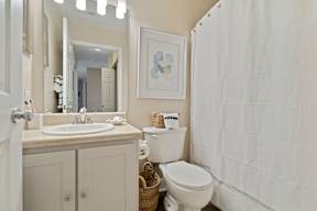 A white bathroom with a toilet, sink, and shower curtain.