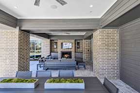 A modern outdoor patio with a fireplace and seating area.