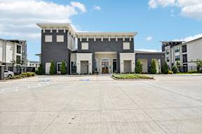 A modern building with a flat roof and a large front yard.