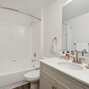 A white bathroom with a toilet, sink, and shower.