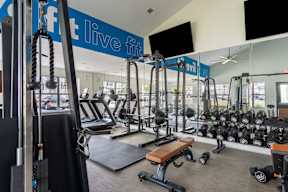 A gym with a variety of equipment including weights and treadmills.