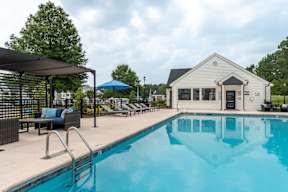 A pool with a blue umbrella and a white building in the background.