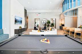 A pool table is in the middle of a room with a couch and a chair.