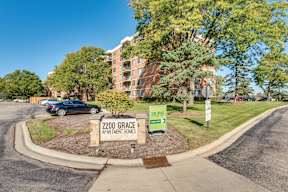 A sign for 2200 Grace Apartment Homes is in front of a parking lot.
