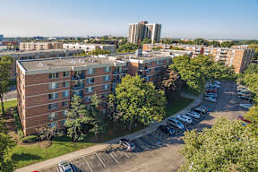 A parking lot is in front of a large apartment building.