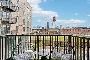 Two chairs with leopard print cushions are on a balcony overlooking a cityscape.