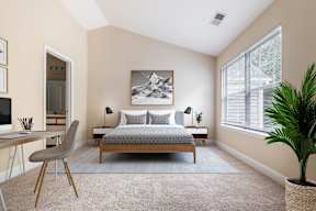 A bedroom with a bed, desk, chair, and a painting on the wall.