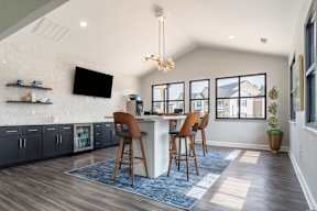 A modern kitchen with a bar stool and a television mounted on the wall.