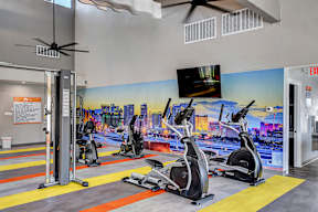 a gym with cardio equipment and a mural of a city on the wall