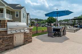 A blue umbrella is in the middle of a concrete patio.