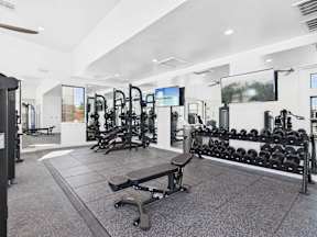 A gym with a variety of equipment including weights and treadmills.