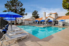 a swimming pool with lounge chairs and umbrellas