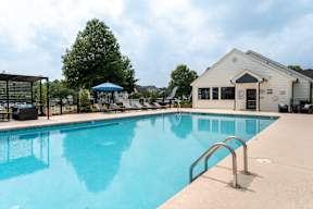 A large swimming pool with a diving board and a building in the background.