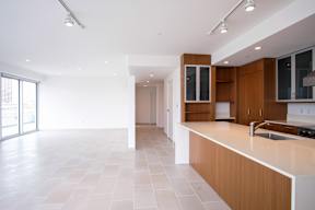 A modern kitchen with a white countertop and wooden cabinets.