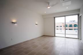 A large empty room with tiled flooring and a sliding glass door.