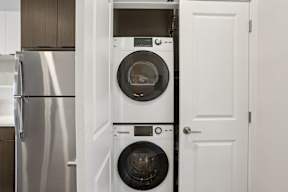 A white door is open to reveal a washing machine and dryer.
