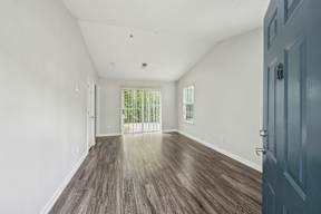 A room with a wooden floor and a door on the right side.