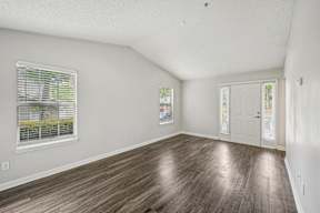 A room with wooden flooring and a window with blinds.