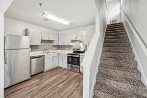A kitchen with a staircase leading to the upper floor.