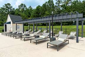 A row of sun loungers are arranged on a concrete surface.