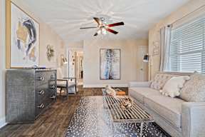 A living room with a grey couch, a coffee table and a ceiling fan.
