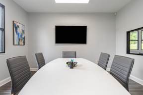 A conference room with a white table and black chairs.