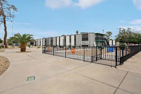 A black fence surrounds a concrete area with a building in the background.
