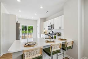 A kitchen with white cabinets and green chairs.
