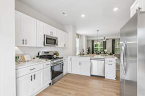 A modern kitchen with white cabinets and stainless steel appliances.