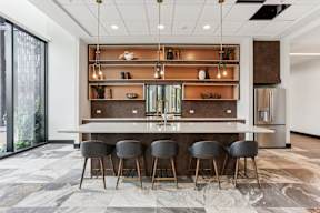A modern kitchen with a bar area and grey chairs.