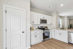A kitchen with white cabinets and appliances.