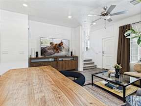 A living room with a wooden table and a painting of two dogs on the wall.
