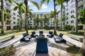 a patio with chairs and palm trees in front of an apartment building
