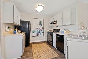 A kitchen with white cabinets and a black refrigerator.