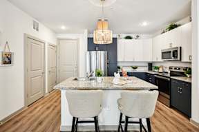 A kitchen with a granite countertop and two chairs.