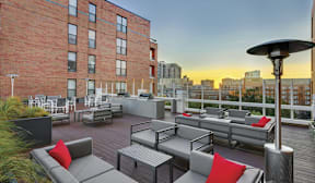 A patio with grey couches and tables is set up on a rooftop.