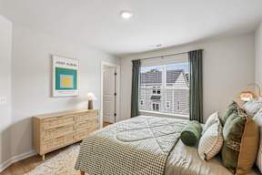 A bedroom with a bed, dresser, and a painting by Josef Albers.